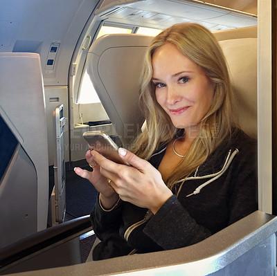 Buy stock photo Portrait of a young woman using her cellphone while sitting in first class in an airplane