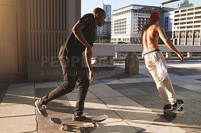 Buy stock photo Shot of two young men skating in the city
