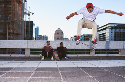 Buy stock photo Shot of a young man doing tricks on his skateboard while his friends looks on