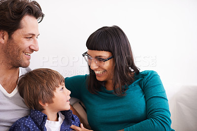 Buy stock photo Shot of a young family sitting on a couch