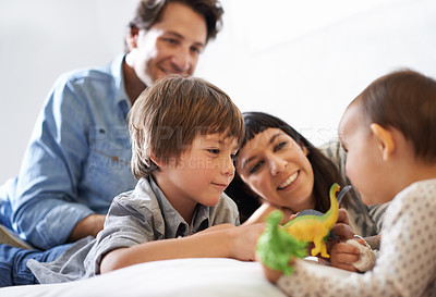 Buy stock photo Shot of a happy brother and sister playing with their toys while their parents look on