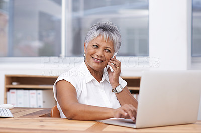 Buy stock photo Shot of a mature businesswoman talking on the phone while using a laptop