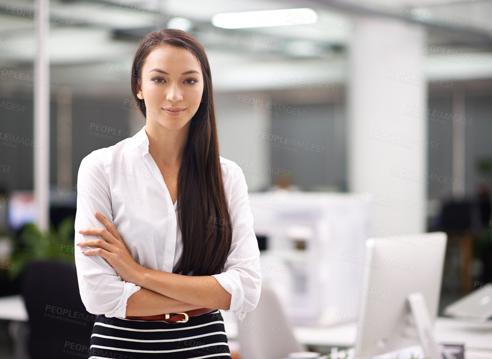 Buy stock photo Portrait of an attractive young businesswoman standing with her arms folded in the office