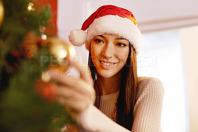 Buy stock photo Cropped shot of an attractive young woman decorating a Christmas tree