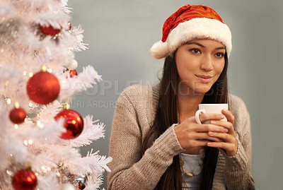 Buy stock photo Cropped shot of an attractive young woman enjoying a hot drink on Christmas eve