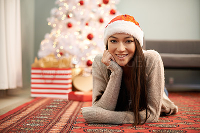 Buy stock photo Portrait, smile and Christmas with young woman in living room of home for festive celebration. Face, gift or present and happy relaxed person with Santa hat in apartment for December holiday season