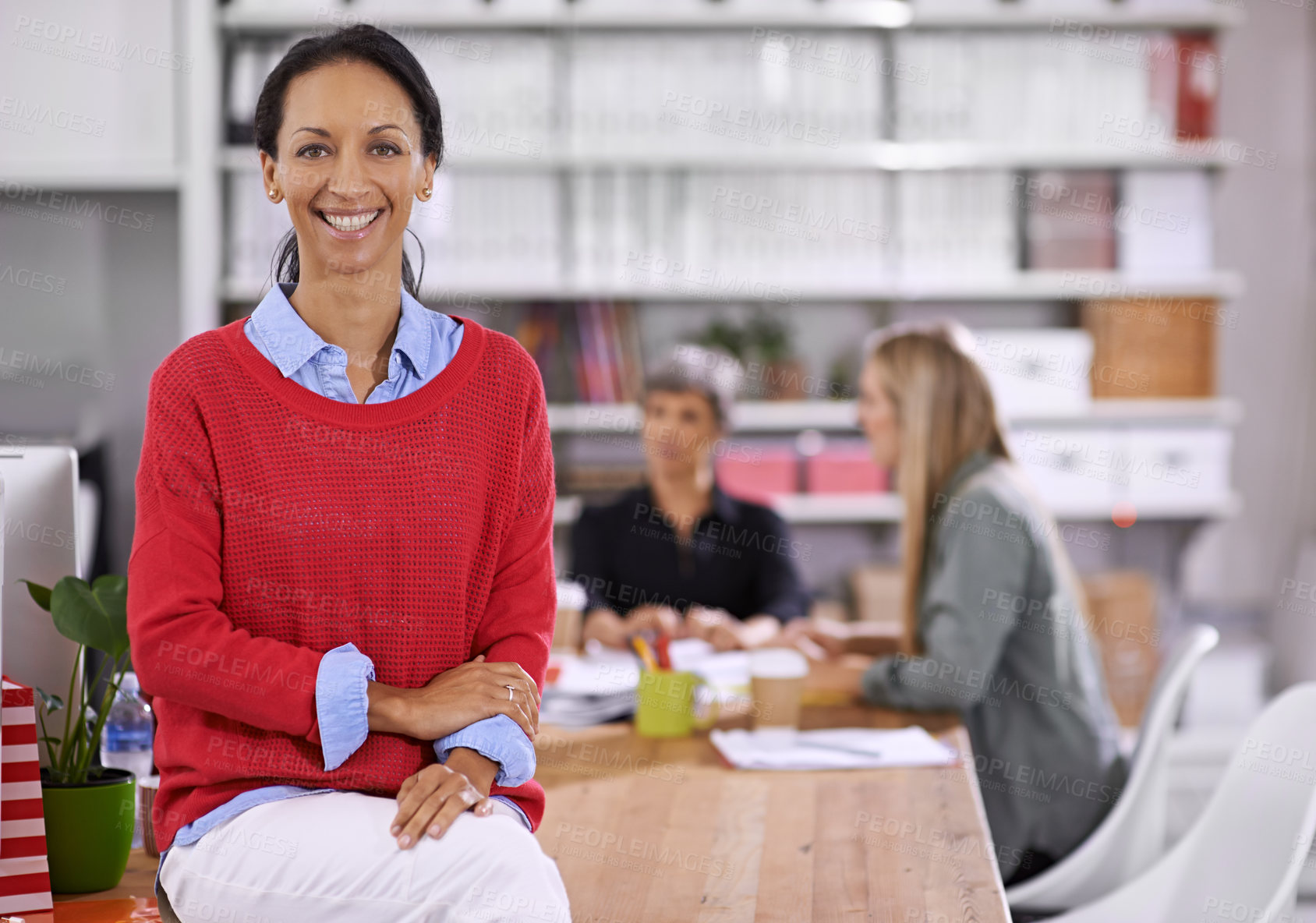 Buy stock photo Portrait of a confident young businesswoman with her colleagues working in the background