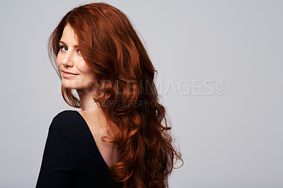 Buy stock photo Studio shot of a young woman with beautiful red hair posing against a gray background