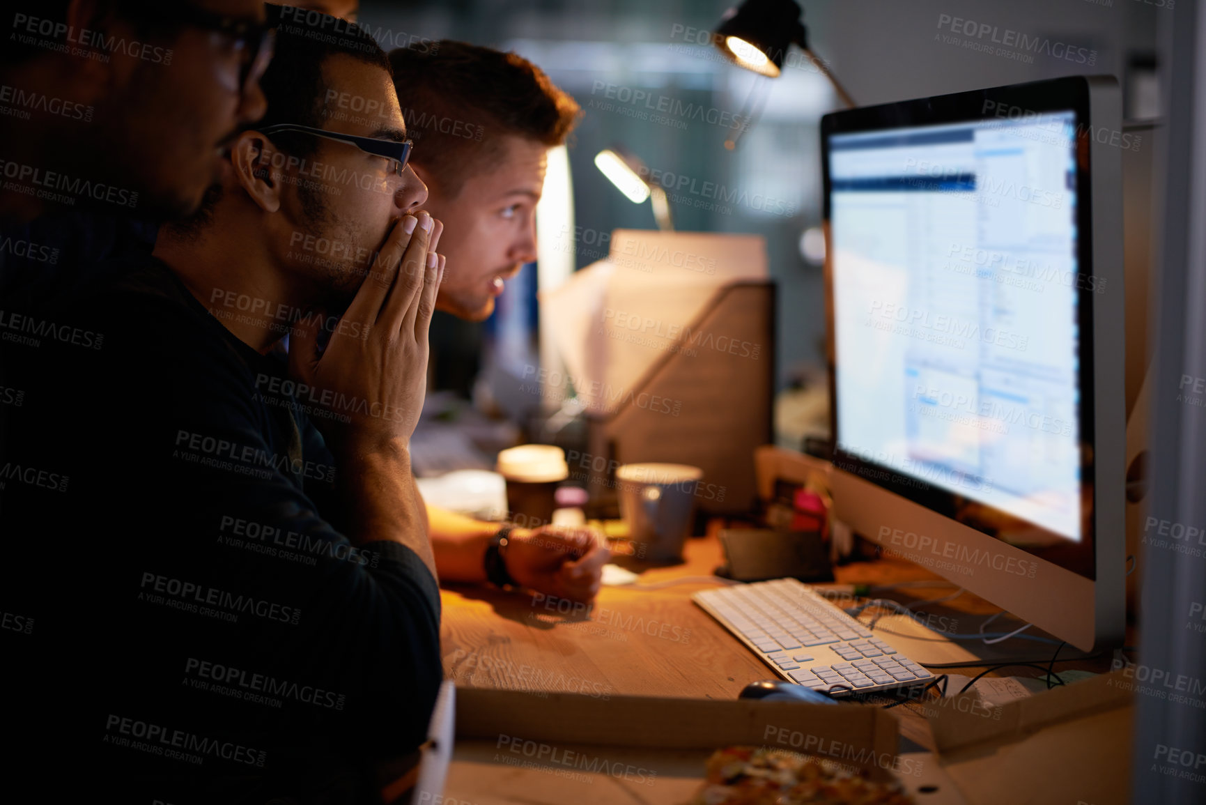 Buy stock photo Cropped shot of a group of young coworkers working in a dimly-lit office