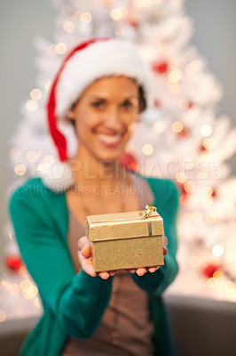 Buy stock photo Shot of a beautiful young woman holding out her Christmas present