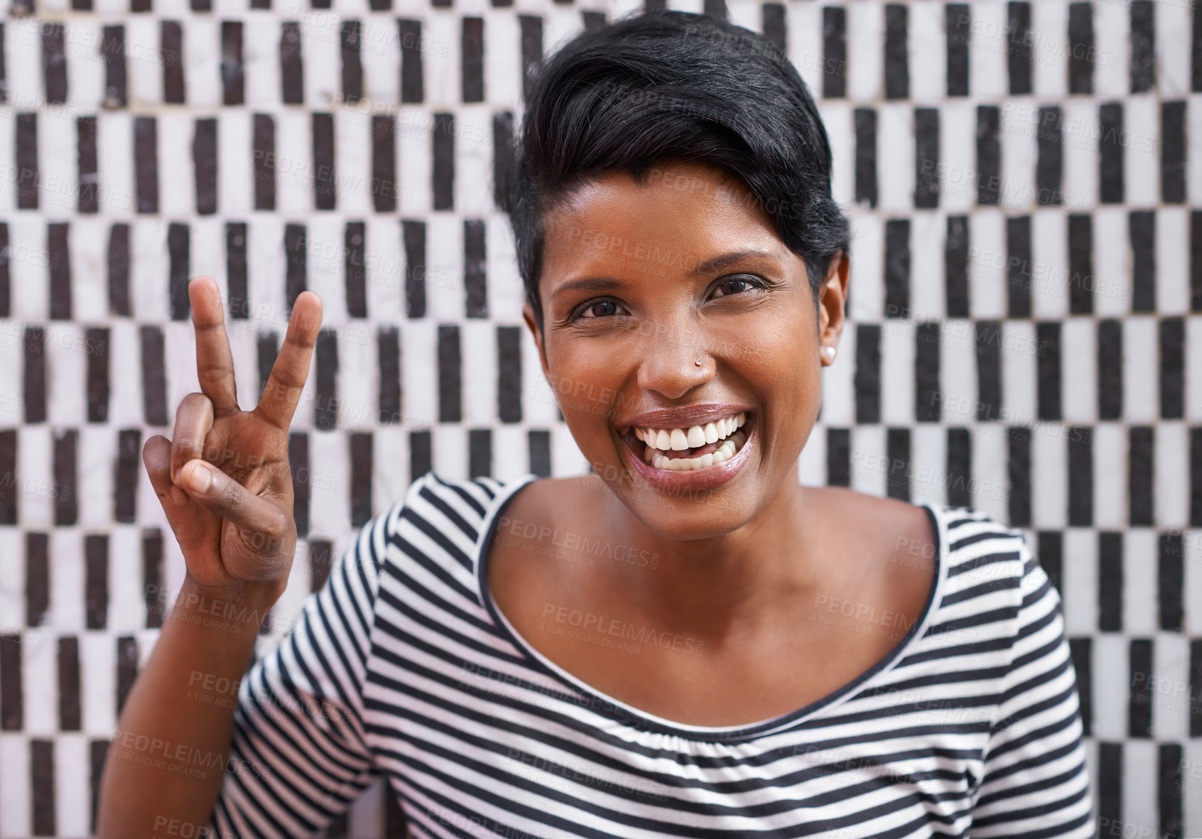 Buy stock photo A cropped portrait of a beautiful young woman in stripes standing against a checkered wall