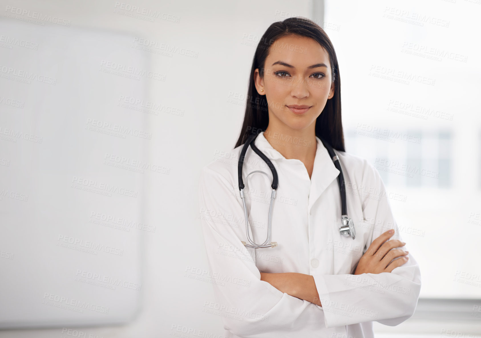 Buy stock photo Portrait of a confident young doctor standing with her arms folded