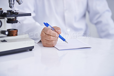 Buy stock photo A cropped shot of a scientist recording observations on a piece of paper while sitting in his lab