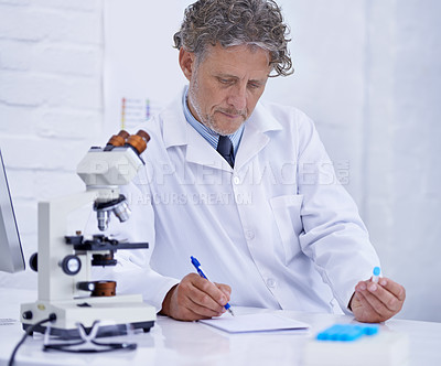 Buy stock photo A mature scientist recording observations on a piece of paper while sitting in his lab