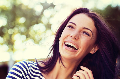 Buy stock photo Shot of a beautiful young woman laughing while standing outside