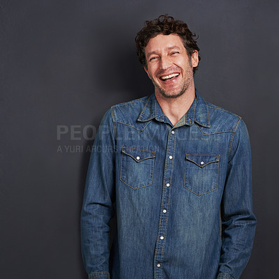 Buy stock photo Studio portrait of a handsome man laughing while standing on a gray background