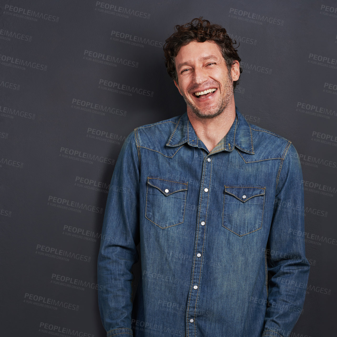 Buy stock photo Studio portrait of a handsome man laughing while standing on a gray background