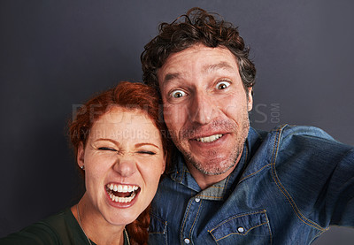 Buy stock photo Selfie, crazy and happy couple in studio together with relationship trust, care and support. Photography, man and woman smile on dark background with commitment, loyalty and affection in fun marriage