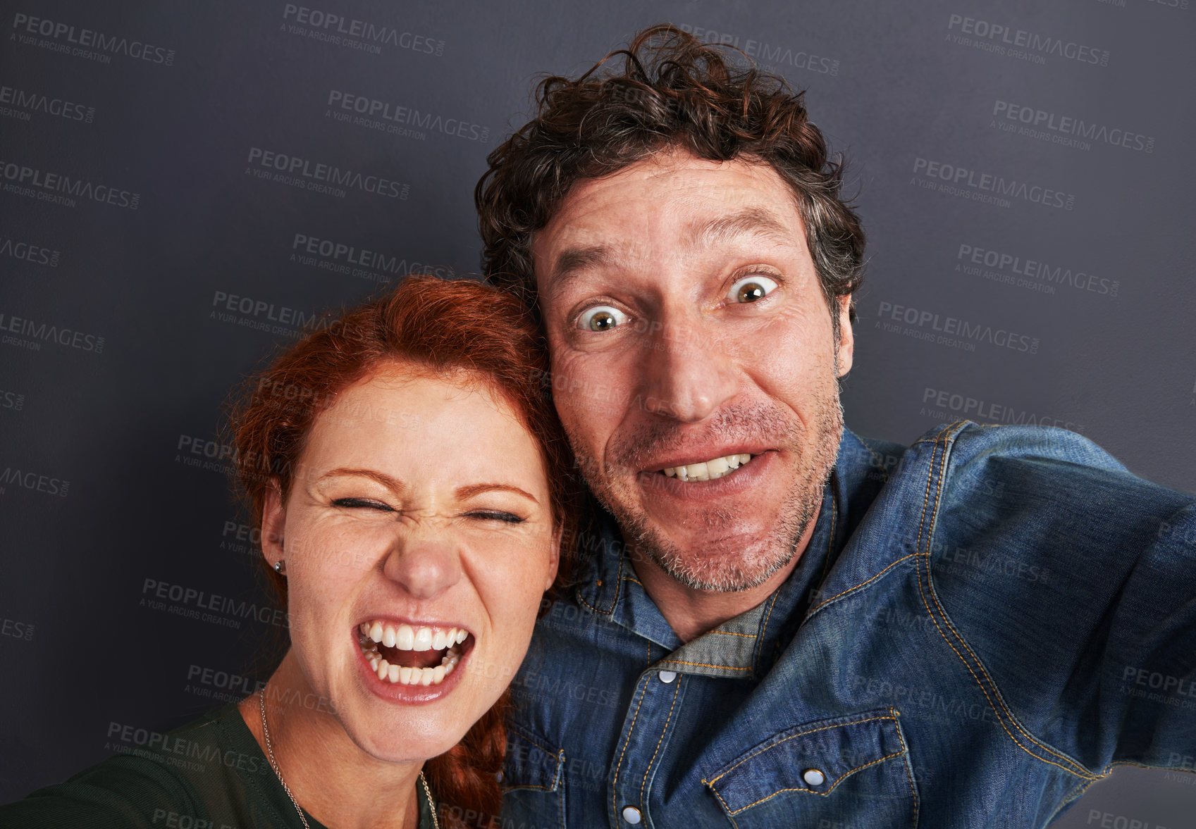 Buy stock photo Selfie, crazy and happy couple in studio together with relationship trust, care and support. Photography, man and woman smile on dark background with commitment, loyalty and affection in fun marriage