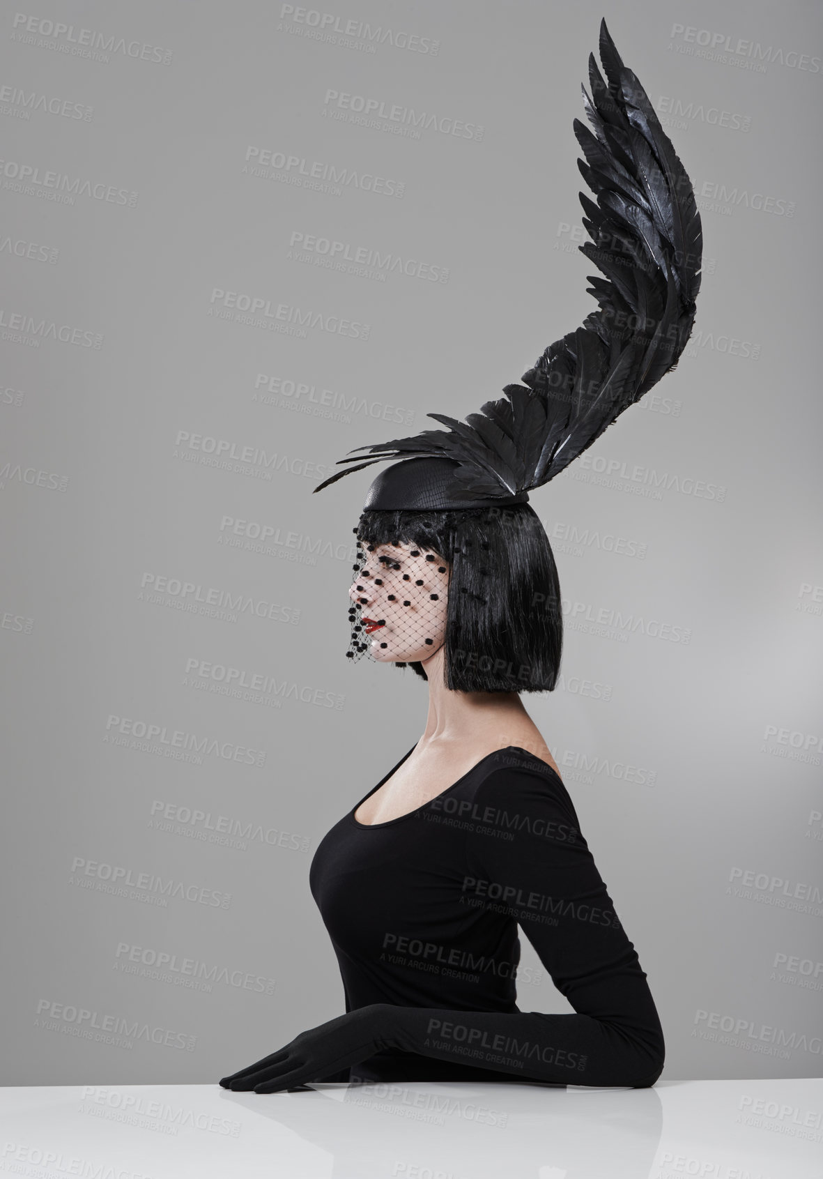 Buy stock photo Shot of a young woman in a wing-shaped headpiece sitting in a studio