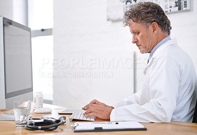 Buy stock photo Shot of a mature doctor using a computer in his office