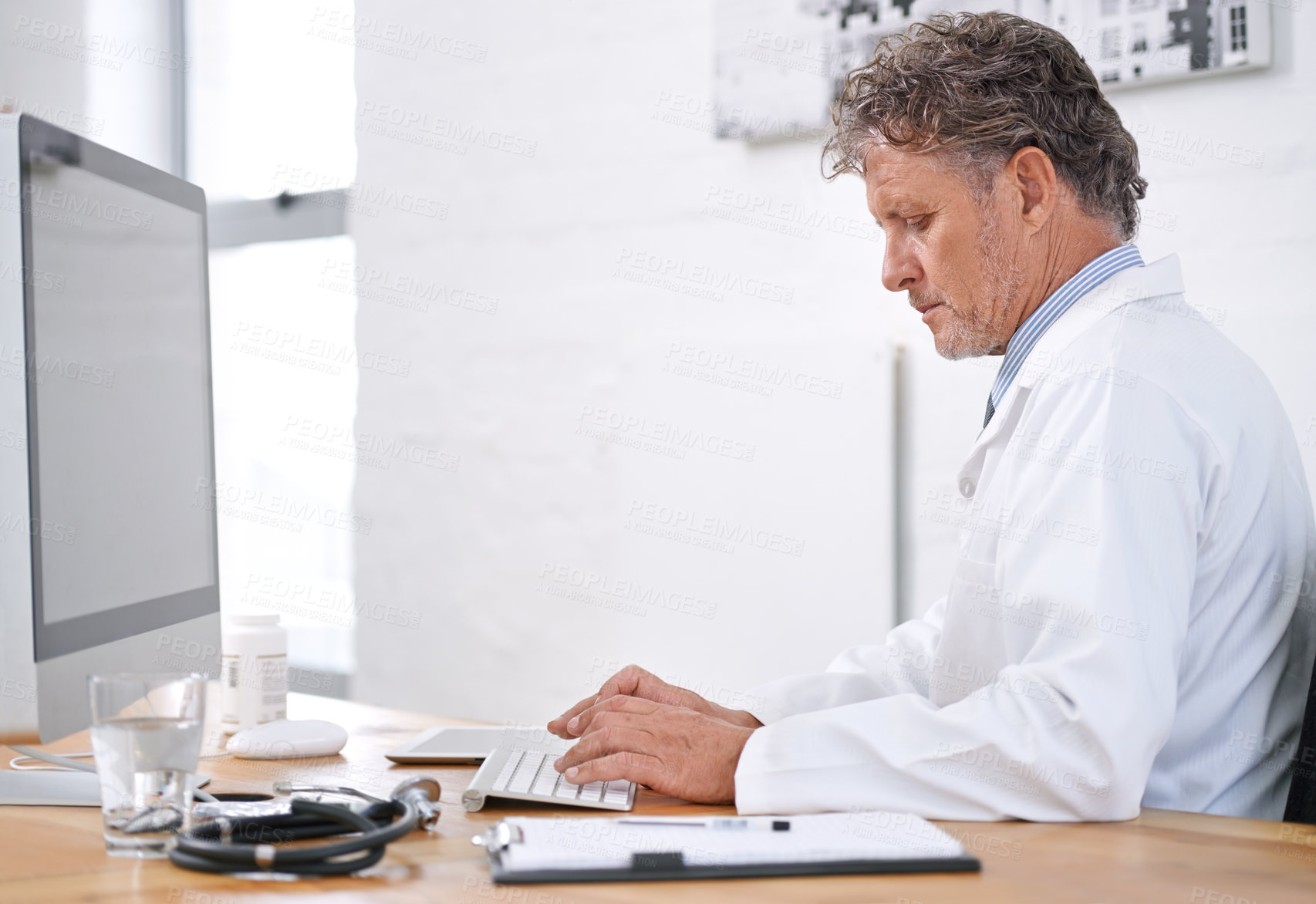 Buy stock photo Shot of a mature doctor using a computer in his office