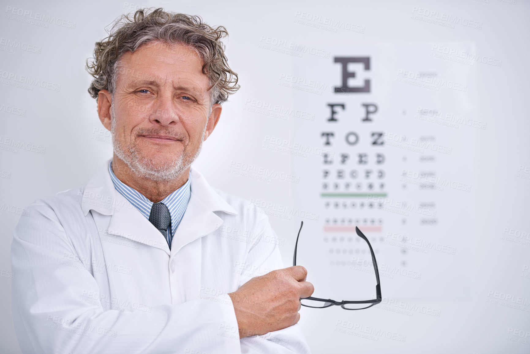 Buy stock photo Eye, test and portrait of optometrist in clinic with glasses to check vision and exam in healthcare. Mature, doctor and reading letters on wall in medical assessment for contact lenses or eyesight