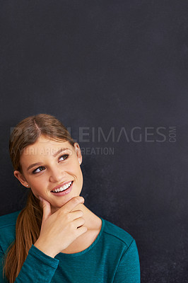 Buy stock photo Shot of a beautiful young woman standing against a blackboard