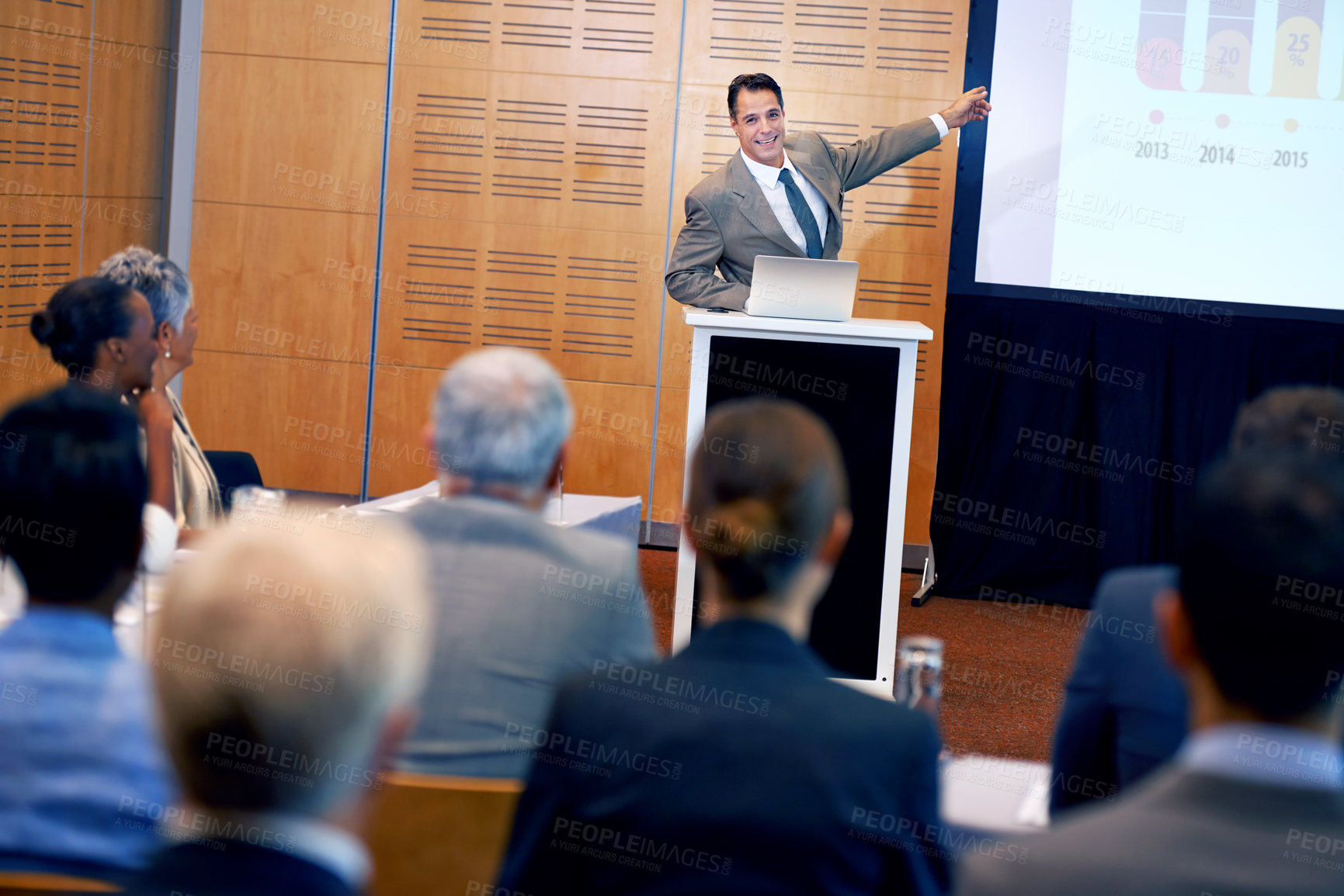 Buy stock photo Businessman, presentation and laptop with projector at conference in team meeting, staff training or seminar. Man, employee or speaker talking on podium to group for corporate growth at workshop