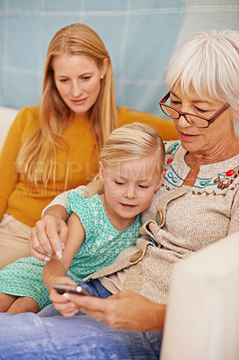 Buy stock photo Girl, phone and social media at a home with grandmother, family and mother together with game. Learning, online and senior woman with child and mom with love, support and care in a house with tech