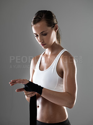 Buy stock photo Woman, fitness and boxer with strapping fists for fight, workout or exercise on a gray studio background. Female person or fighter wrapping hands in preparation or getting ready for sports training