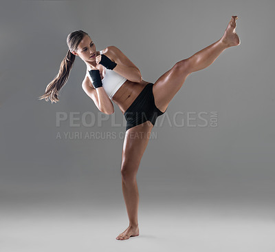 Buy stock photo Full length shot of an athletic young woman practicing her kickboxing technique