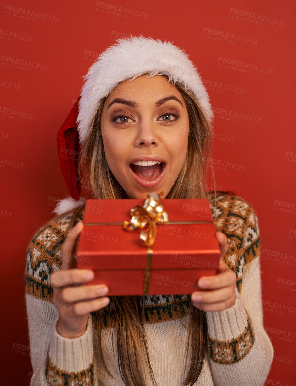 Buy stock photo Excited woman, portrait and Christmas with gift for festive season or December holiday on a red studio background. Happy female person, surprise or wow with hat for special present, prize or offer