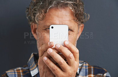 Buy stock photo Mature, man and capture a photo with phone in studio and learning about photography on dark background. Smartphone, recording or filming a video for post online to social media for memory of picture