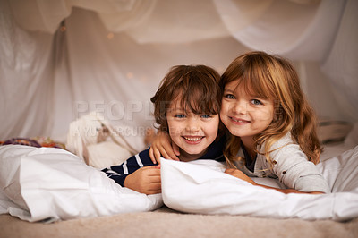 Buy stock photo Shot of two adorable siblings lying in their blanket fort indoors