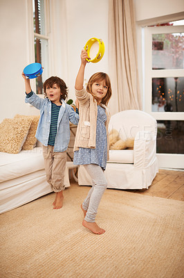 Buy stock photo Shot of two young children playing with tambourines in the living room at home