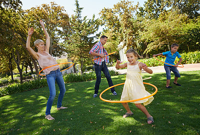Buy stock photo Parents, kids and hula hoop in park for playing, child development and motor skills outdoor. Children, son and daughter with mom and dad in nature for leisure, family time and bonding with smile