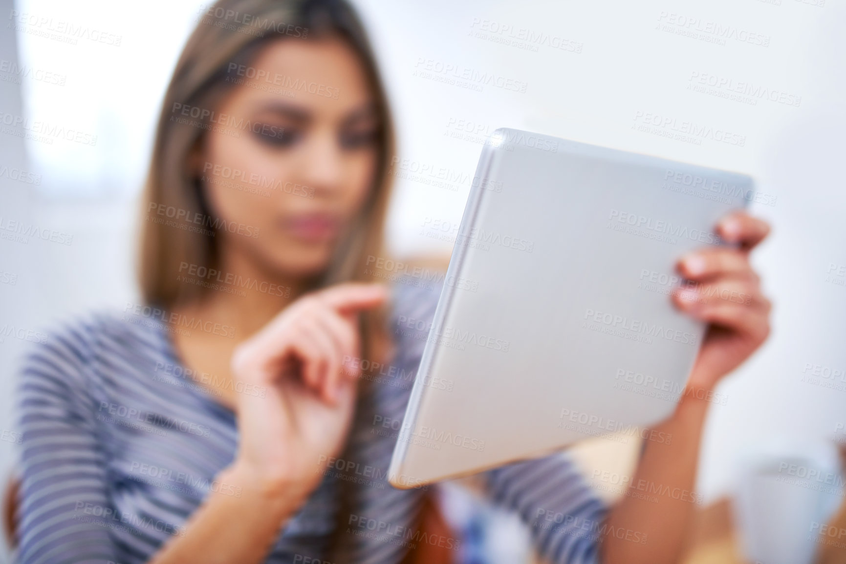 Buy stock photo A cropped shot of a beautiful young professional using a tablet at her desk