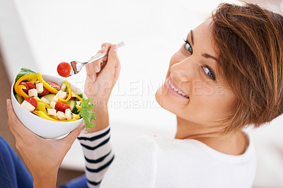 Buy stock photo Shot of a cheerful young woman eating a salad
