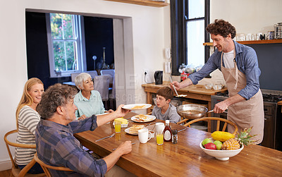 Buy stock photo A cropped shot of a happy man serving his family a deliciously cooked breakfast