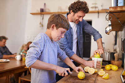 Buy stock photo A cropped portrait of a happy father and son making lemonade in their kitchen at home