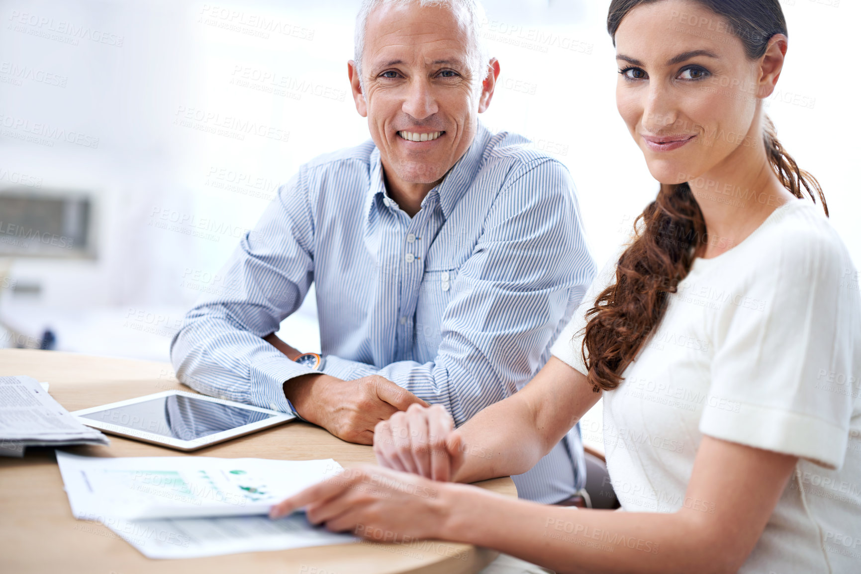 Buy stock photo Shot of two colleagues reading paperwork while sitting at a desk in an office