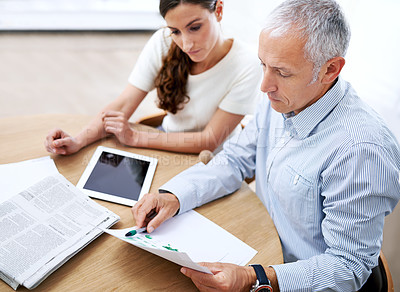 Buy stock photo Meeting, man and woman in office with paperwork for sales review, stats growth or development. Planning, strategy and business people at desk with tablet, newspaper and data analysis on profit trends
