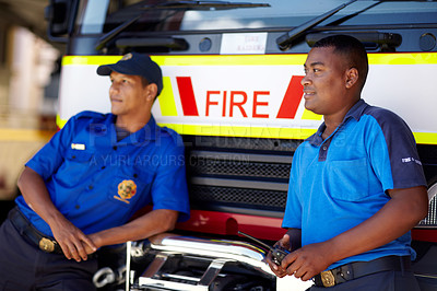 Buy stock photo Shot of two firemen leaning on their truck