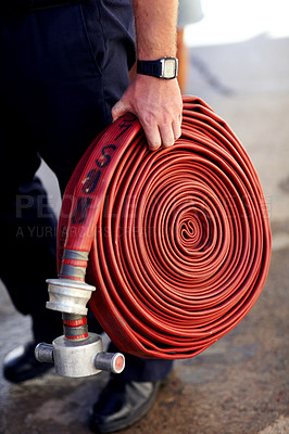 Buy stock photo Closeup shot of a fireman carrying a coiled fire hose