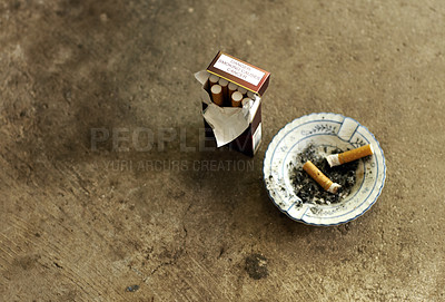 Buy stock photo Shot of an ashtray, cigarette butts and a pack of cigarettes