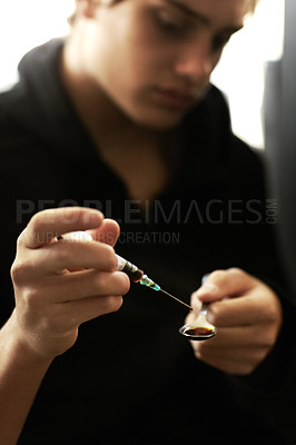Buy stock photo Shot of a young man preparing a shot of heroin