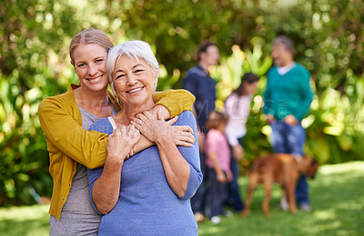 Buy stock photo Shot of a mother and her adult daughter with family in the background