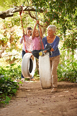Buy stock photo Elderly woman, tire swing and grandma playing with grandkids or holidays and having fun in a garden in summer. Excited, grandchildren and outdoors swinging together or on sunny weekend at a park