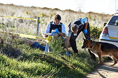 Buy stock photo Shot  of two investigators taking notes while examining a body at a crime scene